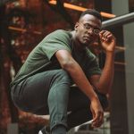 A contemporary portrait of a young man posing confidently outdoors with vibrant green tones.
